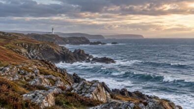 Clouds above a British coastline with rough sea and a distant lighthouse