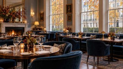 A warmly lit London-style dining room with wooden tables and blue upholstered seating